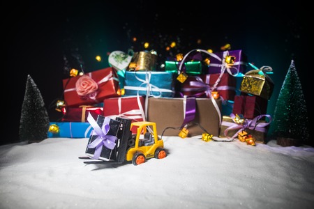 New year or Christmas holiday shopping concept. Store promotions.. Forklift caryying a gift on snow. Stack of gift boxes on background. Sticker with empty space for your textの写真素材