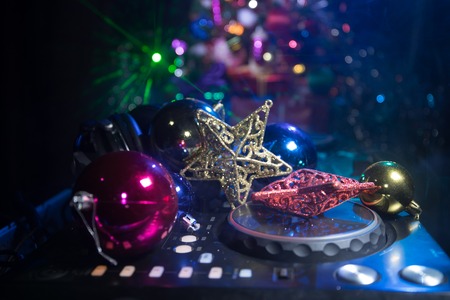Dj mixer with headphones on dark nightclub background with Christmas tree New Year Eve. Close up view of New Year elements on a Dj table. Holiday party concept. Empty spaceの写真素材