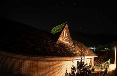 Stars over the house late at night, beautiful night sky, roof of the house, autumn night. Long exposureの写真素材