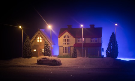 Little decorative cute small houses in snow at night in winterの写真素材