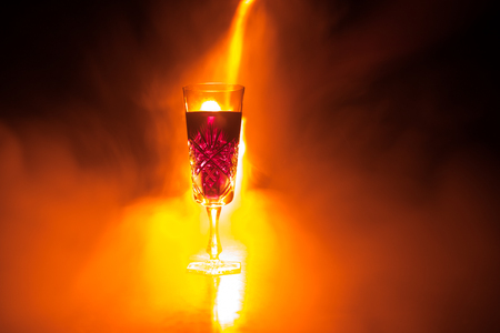 Wine glass in fire concept. One glass of red wine with burning fire on black background. Selective focus. Empty spaceの写真素材