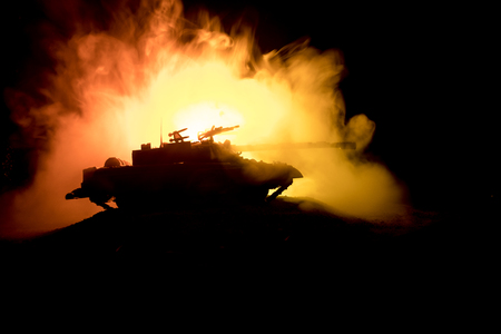 War Concept. Armored Tank Silhouette Below foggy fire sky at night. Attack scene. Toy decoration. Selective focusの写真素材