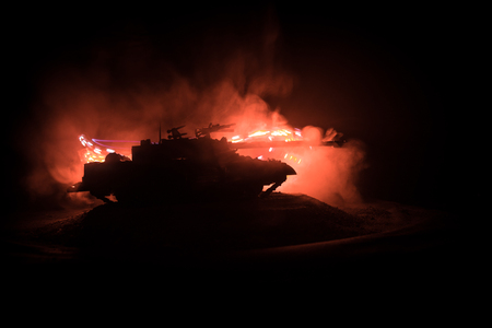 War Concept. Armored Tank Silhouette Below foggy fire sky at night. Attack scene. Toy decoration. Selective focusの写真素材