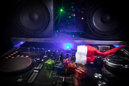 Dj mixer with headphones on dark nightclub background with Christmas tree New Year Eve. Close up...
