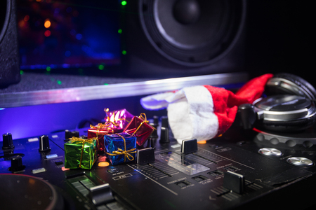 Dj mixer with headphones on dark nightclub background with Christmas tree New Year Eve. Close up view of New Year elements on a Dj table. Holiday party concept. Empty spaceの写真素材