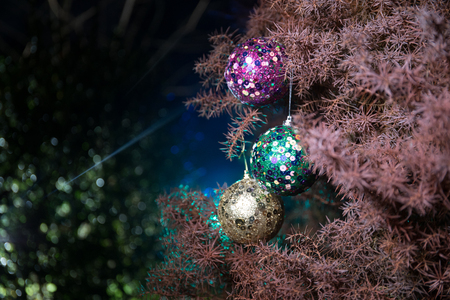 Bauble on tree. Christmas and New Year decoration on the pine tree branch with lights at the background at night outdoors. Concept of winter holidays. Selective focusの写真素材