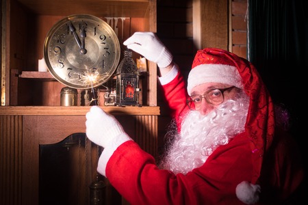 Santa Claus in wooden home interior showing time on a clock. Christmas concept Santa Claus and a large clock. Holiday conceptの写真素材