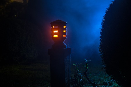 Beautiful colorful illuminated lamp in the garden in misty night. Retro style lantern at night...