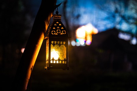 Beautiful colorful illuminated lamp in the garden in misty night. Retro style lantern at night outdoor. Selective focusの写真素材