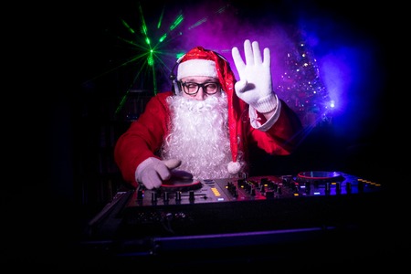 Dj Santa Claus at Christmas with glasses and snow mix on New Year's Eve event in the rays of light. Holiday club conceptの写真素材
