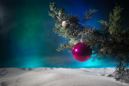 Christmas Decoration - bauble on branch of pine tree with holiday attributes on snow. Selective...
