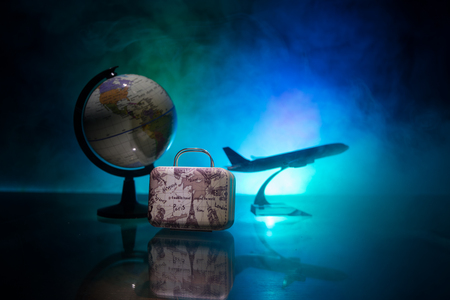 Summer vacation concept. Traveler suitcase with airplane in background. Artwork table decoration with empty space for your text. Focus on suitcase.の写真素材