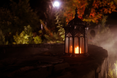 Retro style lantern at night. Beautiful colorful illuminated lamp at the balcony in the garden....