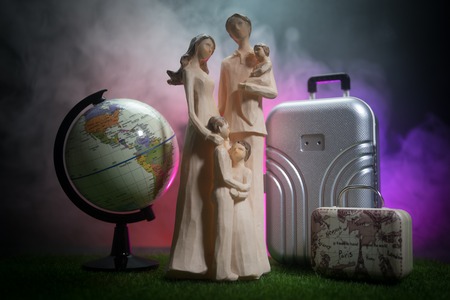 Young family and globe. Travel concept. Family with luggage ready for trip, Artwork on table decoration. Selective focusの写真素材