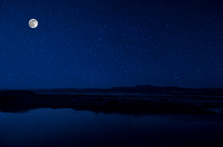 Landscape of gorgeous full moon over the snow-capped mountains reflected in the lake or mysterious night sky with full moonの写真素材