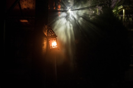 Beautiful colorful illuminated lamp in the garden in misty night. Retro style lantern at night...
