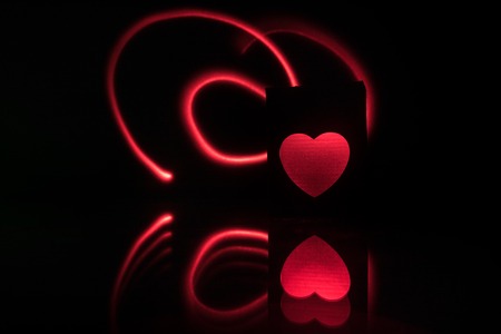Dark table,Valentines day concept and love red shape heart with bokeh background, empty for text and placing products with copy space. Blurred glowing heart on a dark background with reflectionの写真素材