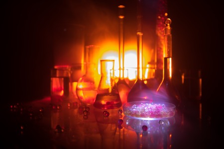 Pharmacy and chemistry theme. Test glass flask with solution in research laboratory. Science and medical background. Laboratory test tubes on dark toned background , science research equipment conceptの写真素材