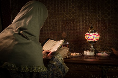 Glass of black tea in woman`s hand at Low light lounge interior with carpet. Eastern tea concept. Eastern snacks on vintage wooden surface. Selective focusの写真素材