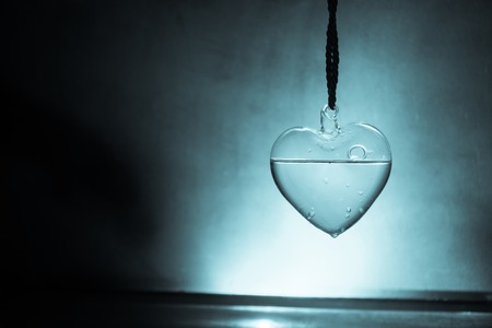 Valentines Day Concept. Glass transparent heart on dark, glass heart glows, glass painting, black...