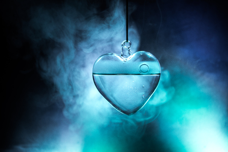 Valentines Day Concept. Glass transparent heart on dark, glass heart glows, glass painting, black background. Emptry space for your textの写真素材