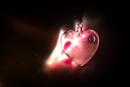Valentines Day Concept. Glass transparent heart on dark, glass heart glows, glass painting, black background. Emptry space for your textの写真素材