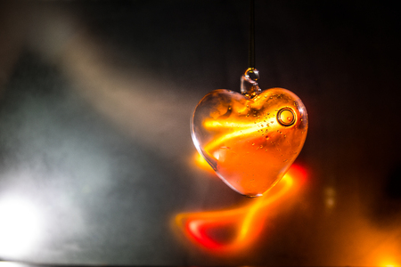Valentines Day Concept. Glass transparent heart on dark, glass heart glows, glass painting, black background. Emptry space for your textの写真素材