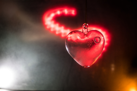Valentines Day Concept. Glass transparent heart on dark, glass heart glows, glass painting, black background. Emptry space for your textの写真素材