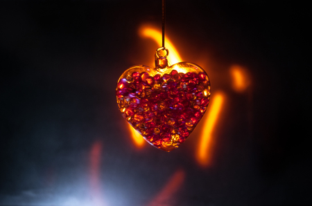 Valentines Day Concept. Glass transparent heart on dark, glass heart glows, glass painting, black background. Emptry space for your textの写真素材