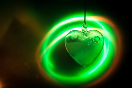 Valentines Day Concept. Glass transparent heart on dark, glass heart glows, glass painting, black background. Emptry space for your textの写真素材