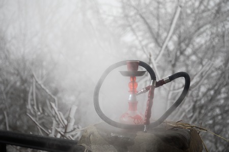 Cold shisha concept. Hookah, traditional arabic waterpipe outdoor photo. Cold winter background. Empty space. Selective focusの写真素材