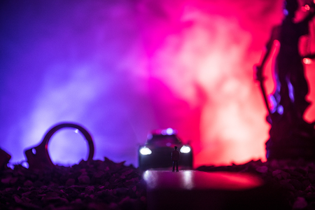 Legal law or crime concept. Man alone standing in the middle of the road on a foggy night. Artwork decoration with handcuffs, Statue of Justice and mallet of justice on toned foggy background.の写真素材