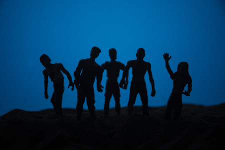 Horror Halloween concept. Silhouettes of scary zombies on misty field walking at the evening. Selective focus. Creative artwork decorationの写真素材