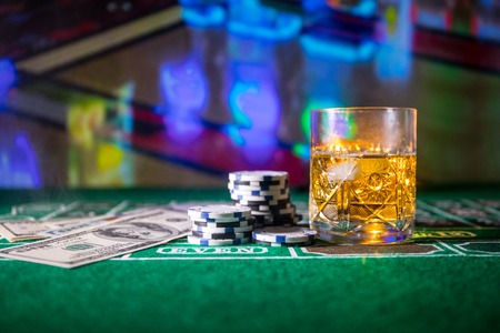gambling, fortune, game and entertainment concept - close up of casino chips and whisky glass on table. Selective focusの写真素材