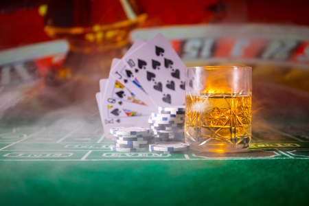 gambling, fortune, game and entertainment concept - close up of casino chips and whisky glass on...