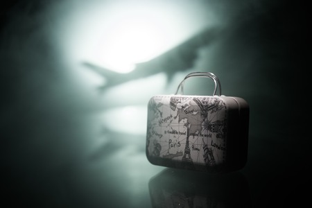 Summer vacation concept. Traveler suitcase with airplane in background. Artwork table decoration...