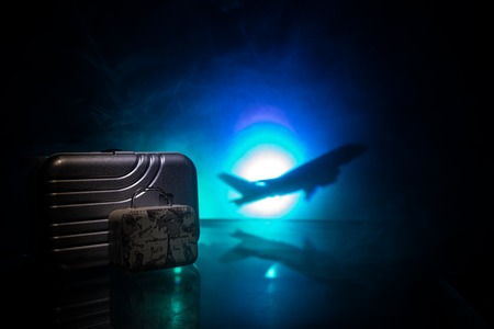 Summer vacation concept. Traveler suitcase with airplane in background. Artwork table decoration with empty space for your text. Focus on suitcase.の写真素材