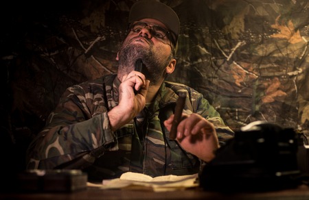 The evil dictator sitting on table. Angry communist general sitting at headquarter or Cuban...