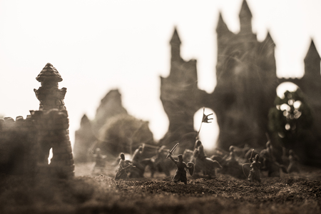 Medieval battle scene with cavalry and infantry. Silhouettes of figures as separate objects, fight between warriors on sunset foggy background. Selective focusの写真素材