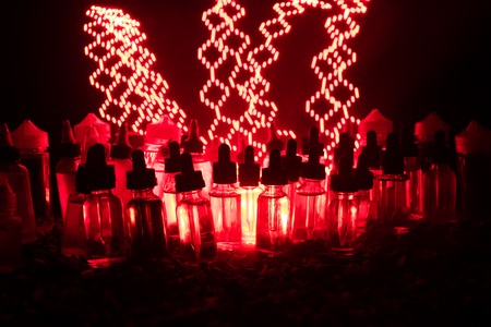 Vape concept. Smoke clouds and vape liquid bottles on dark background. Light effects. Useful as background or electronic cigarette advertisement. Selective focusの写真素材