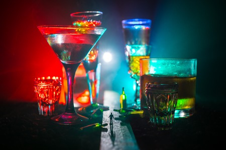 Abstract alcoholism concept. Silhouette of a man standing in the middle of the road on a misty night with giant glasses filled with alcoholic beverage. Creative artwork decorationの写真素材