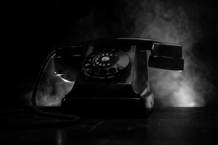 old black telephone on old wood plank with art dark background with fog and toned light. empty...
