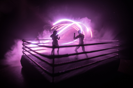 Man and woman boxing on the ring. Sport concept. Artwork decoration with toys on foggy toned dark background.の写真素材