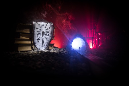 Time concept. Silhouette of a man standing between hourglasses with smoke and lights on a dark background. Surreal decorated pictureの写真素材
