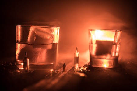 Abstract alcoholism concept. Silhouette of a man standing in the middle of the road on a misty night with giant glasses filled with alcoholic beverage. Creative artwork decorationの写真素材