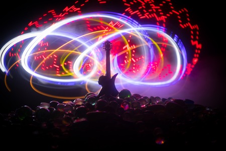 Music concept. Acoustic guitar on a dark background under beam of light with smoke. Emptry space for text. Fire effects. Surreal guitarの写真素材