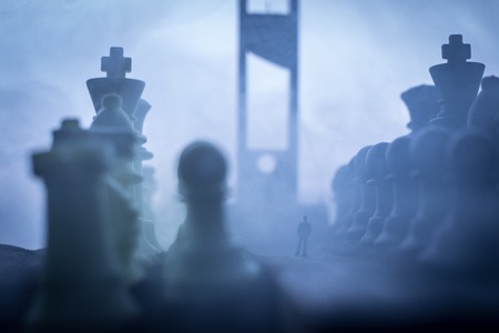 Chess concept of business and strategy ideas. Silhouette of a man standing in the middle of the road with giant chess figures and Guillotine. Artwork decoration. Selective focusの写真素材