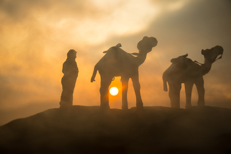 Camel caravan going through the sand dunes in the desert at sunset. Eastern travel concept. Artwork decorationの写真素材