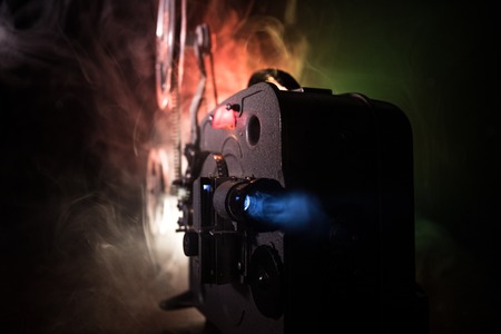 Old vintage movie projector on a dark background with fog and light. Concept of film-making. Selective focusの写真素材