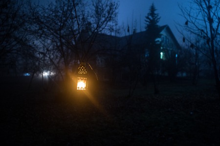 Old house with a Ghost in the forest at night or Abandoned Haunted Horror House in fog. Old mystic building in dead tree forest. Trees at night with moon. Surreal lights. Horror Halloween conceptの写真素材